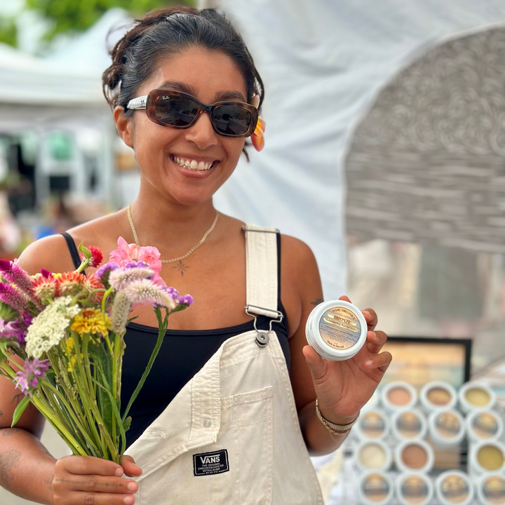 Woman holding flowers and a container, with a blurred background