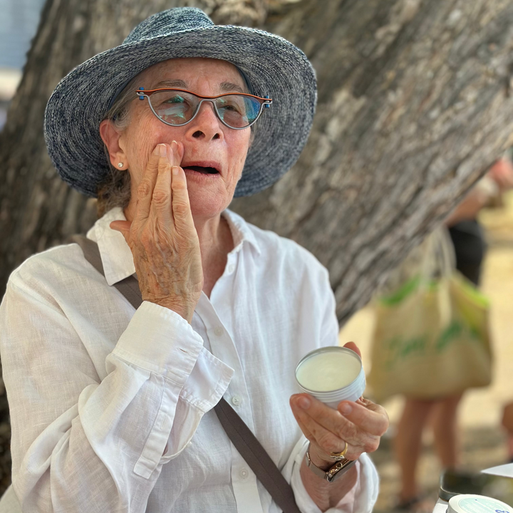 Woman applying sunscreen outdoors under a tree