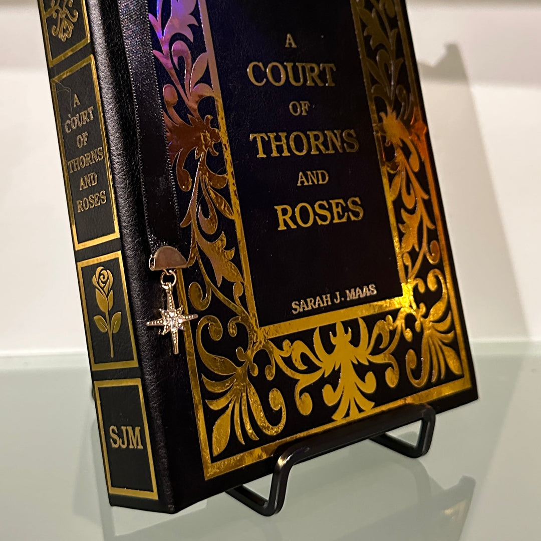 Decorative book titled 'A Court of Thorns and Roses' on a stand with ornate cover